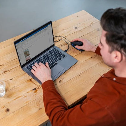 homme pull rouge assis devant ordinateur tenant souris ergonomique