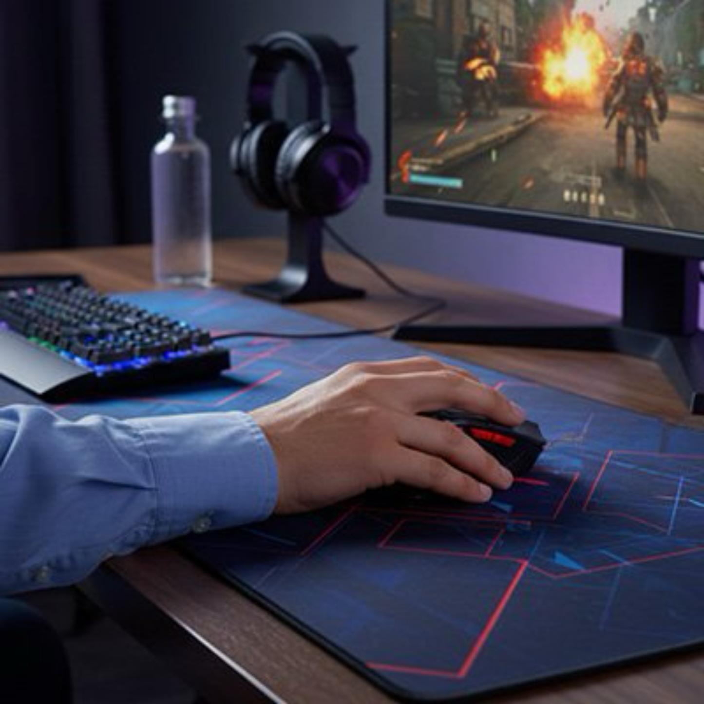 main posée sur souris ergonomique gamer devant écran